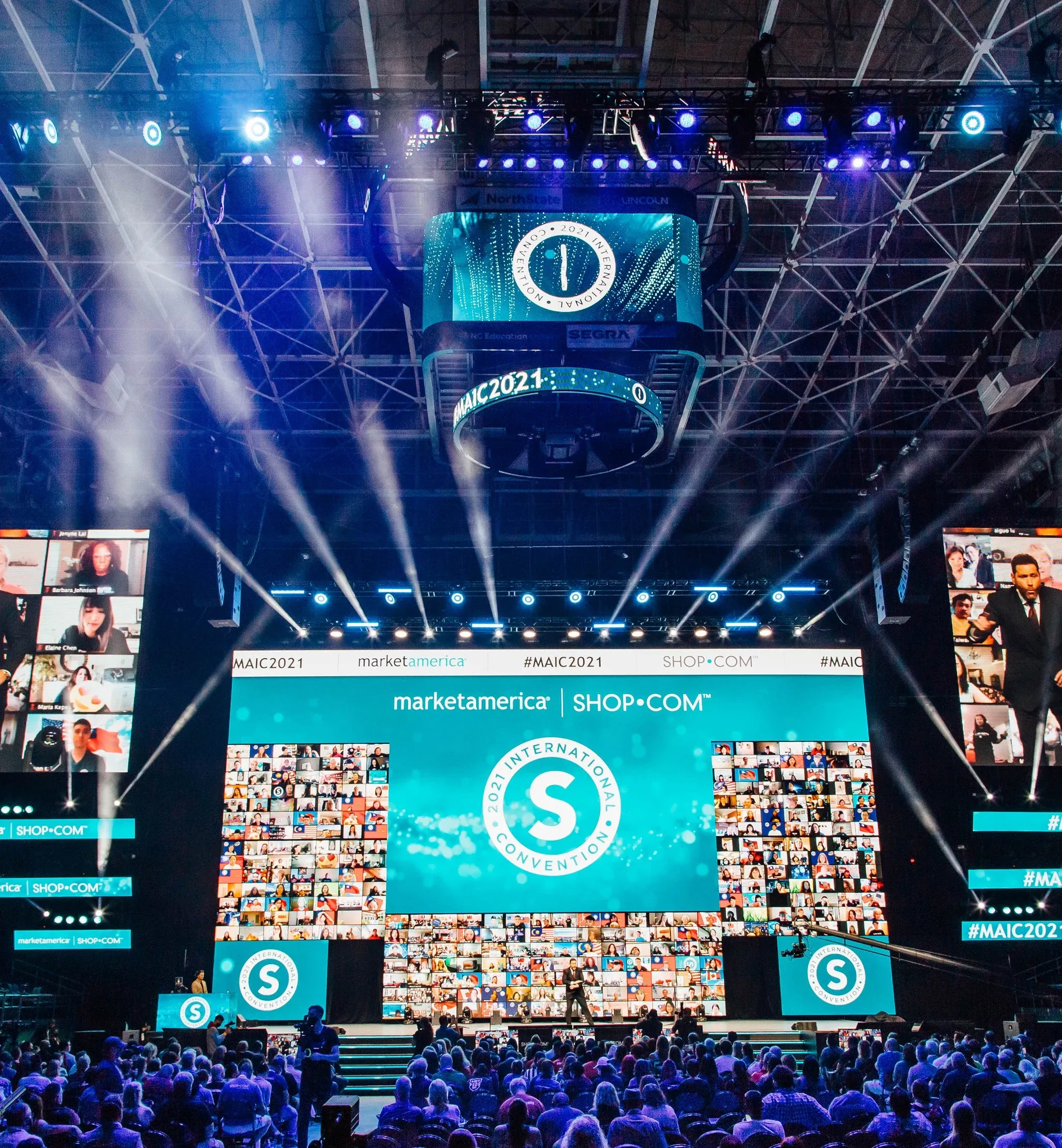 Market America stage with 2021 International Convention logo, virtual-attendee walls, beam lights and center-hung #MAIC2021 ring