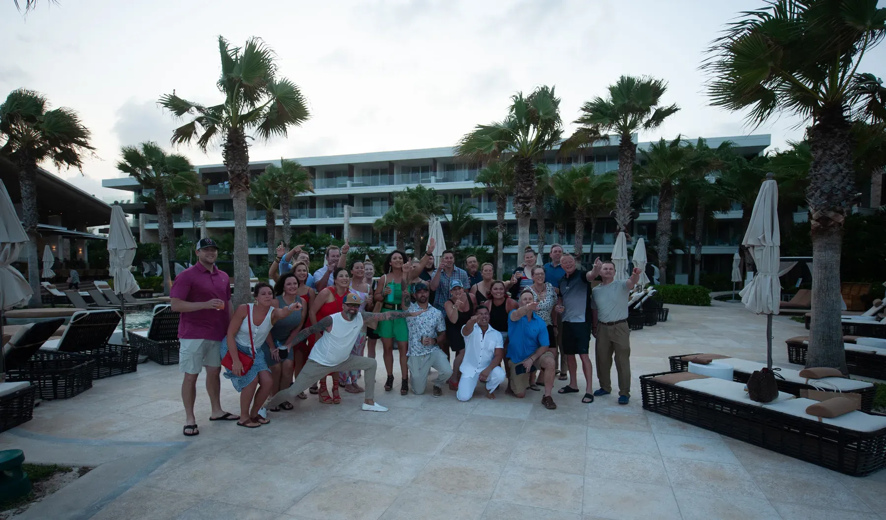IDLife incentive group poses together on the pool deck among palm trees