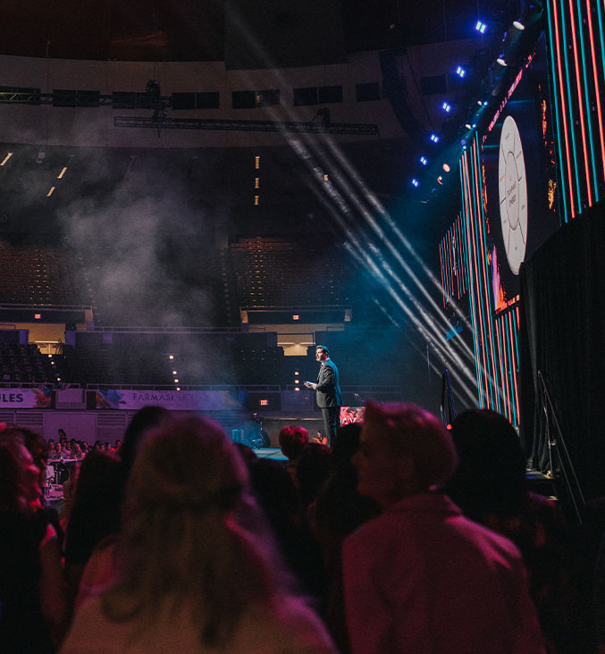 dj wearing black leather jacket with arms raised to crowd in a spotlight