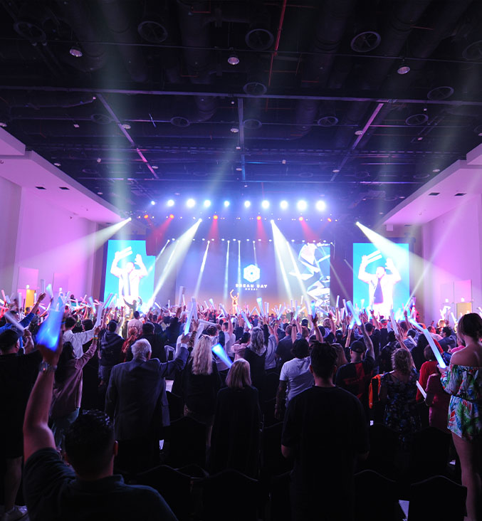 dj wearing black leather jacket with arms raised to crowd in a spotlight