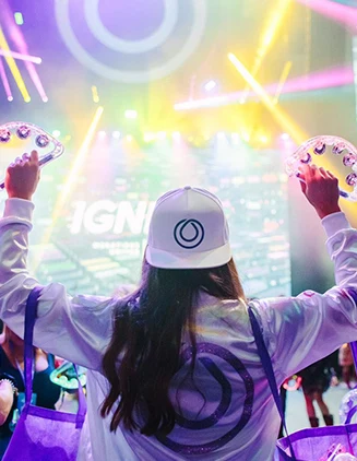 woman with back to camera cheering in front of massive stage with colorful lightshow